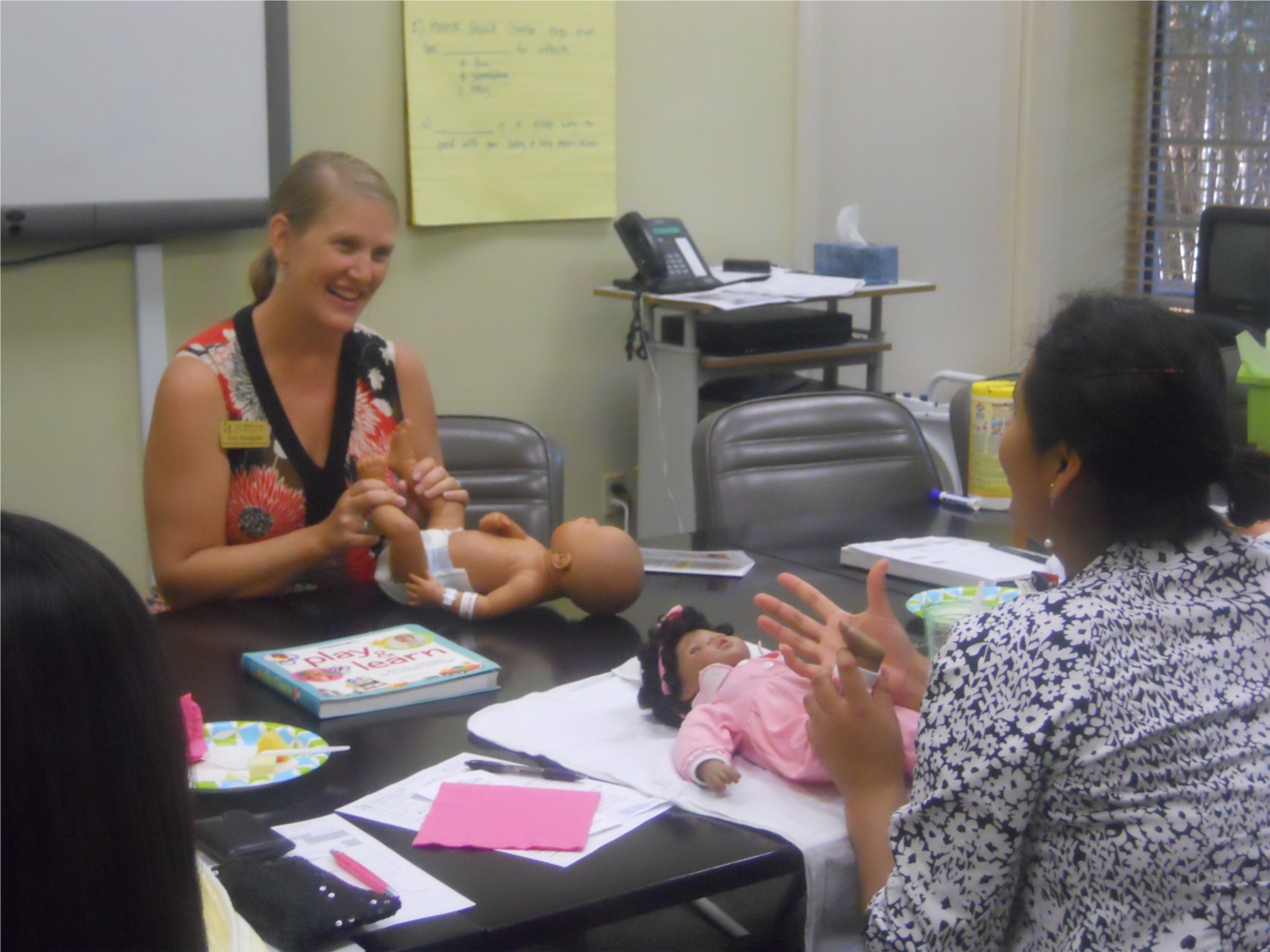 Parenting Education Instructor, Erin Stangland, (left) works one-on-one with a new mother to teach her how to care for her newborn.