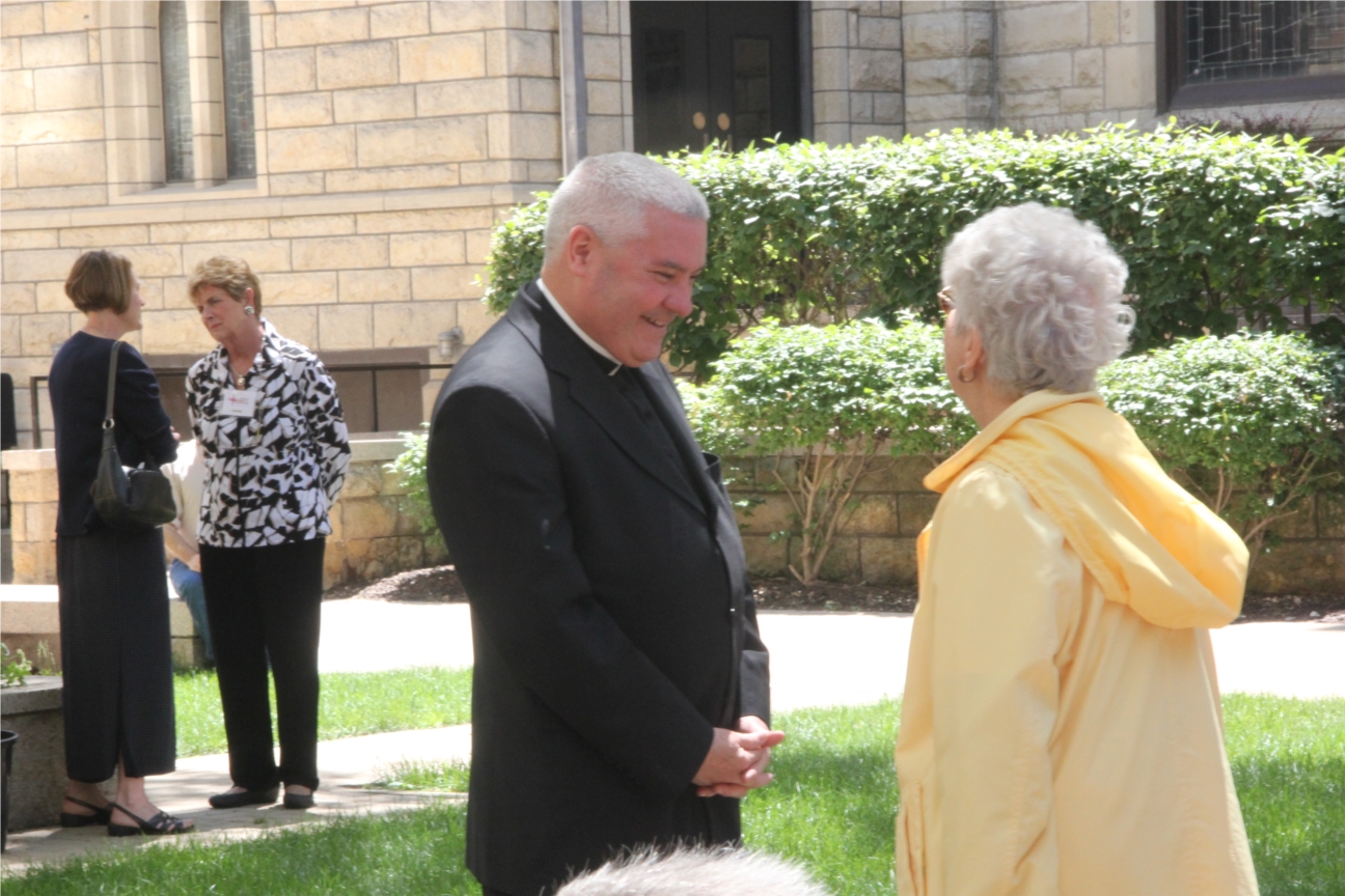 Monsignor Boland, CEO of Catholic Charities, visits with a senior citizen about Catholic Charities programs.