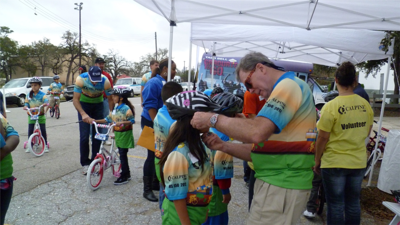Calpine Director of Finance Fred Stachowiak adjusts a biking helmet for a Boys & Girls Club member at the Havard Boys & Girls Club on Airline Drive.  Calpine employees bought and built 110 bicycles that they donated to children served by five local organizations during two holiday bike rallies in December 2012.