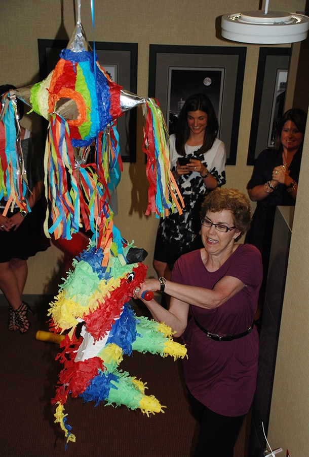 Owner Cindy Nichols attempting to take out a piñata at a monthly birthday celebration.