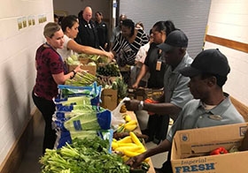 A photo of Hyatt colleagues browsing through some fresh produce that is sold at hotel cost. 