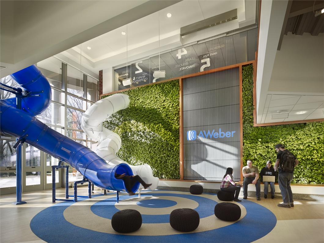 AWeber’s world headquarters exemplifies AWeber’s  5 Core Values in an architectural design. Two 14-feet-high slides descend from the second floor into the atrium, which also has a biowall featuring over 2,000 plants and a two-story rain curtain.