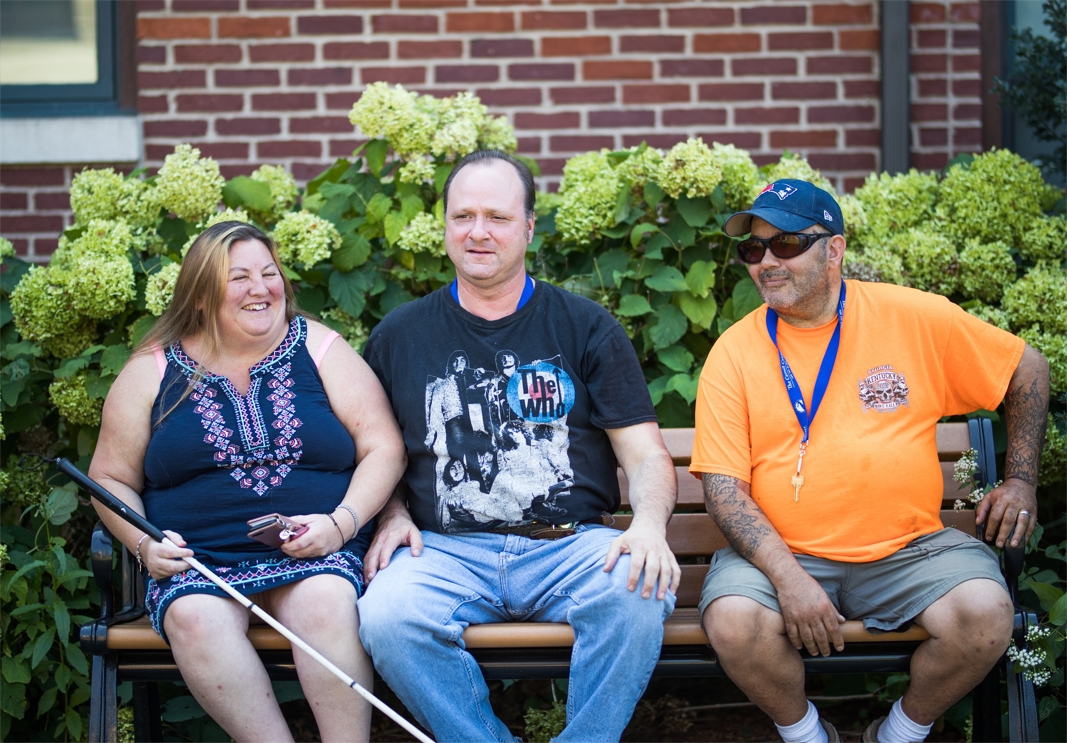 Three clients laugh while seated on a bench during their program at the Carroll Center for the Blind.