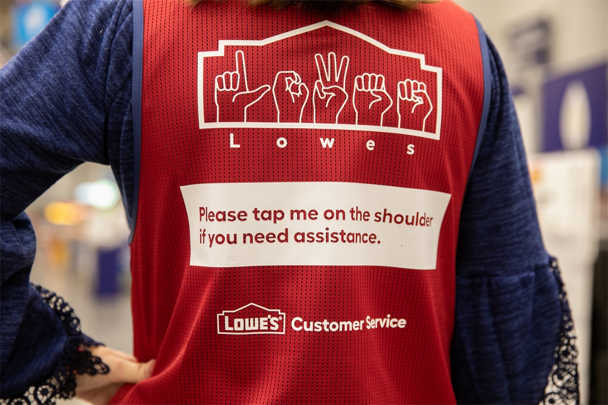 Lowe's red vest that has Lowe's in American Sign Language and says Please tap me on the should if you need assistance.