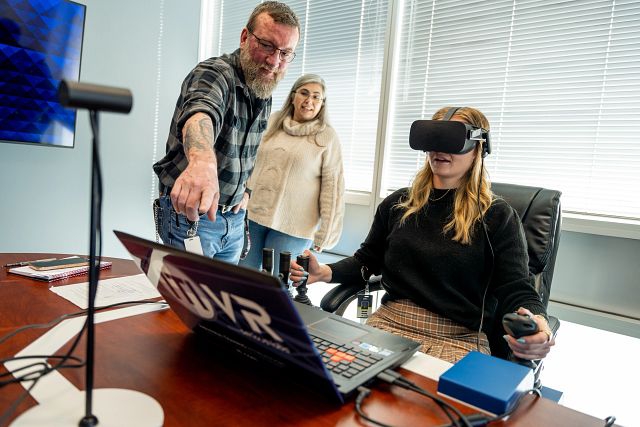 Office employees testing out a new crane simulator to train employees how to operate a crane virtually