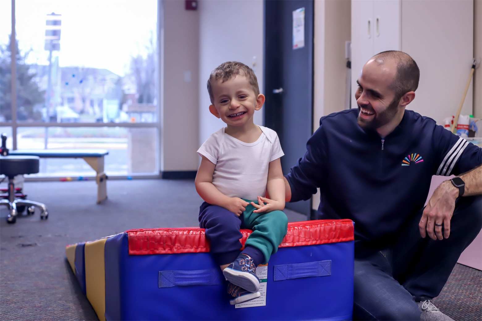 A young client is all smiles while working on sitting balance with a PT.