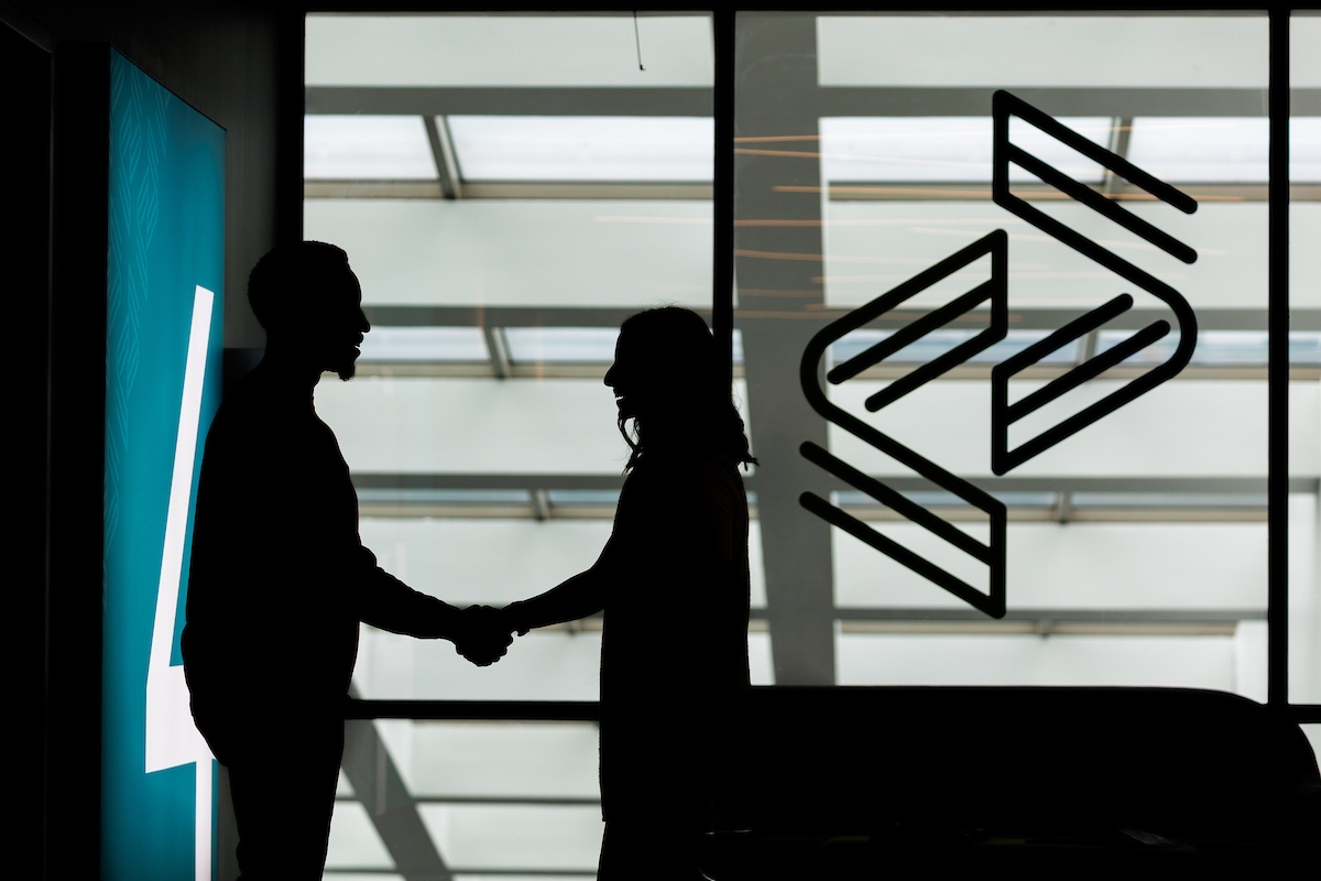 shadow of employees shaking hands in front of Reliance Partners logo