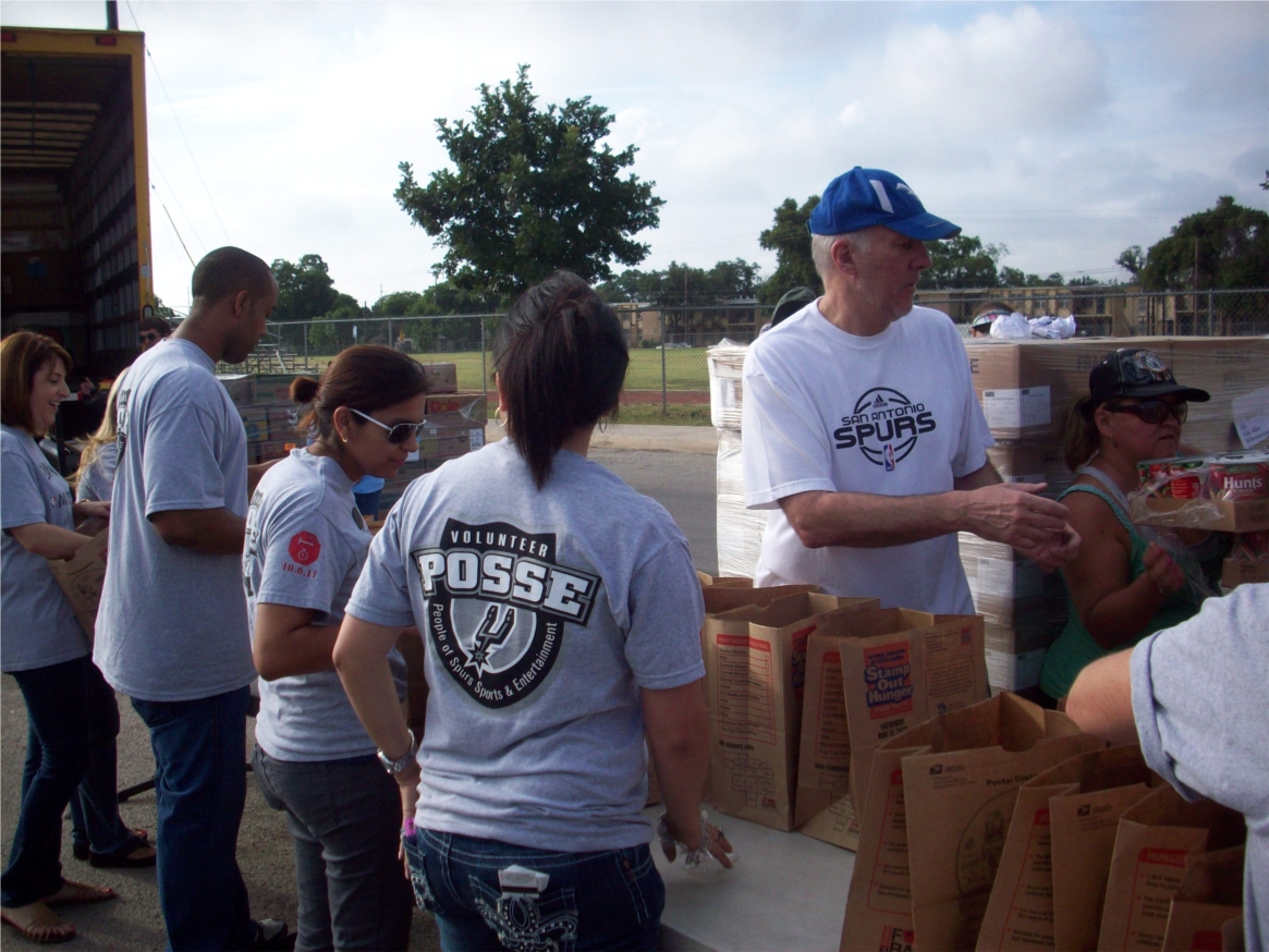 Coach Popovich lends a hand with POSSE members distributing food provided by the S.A. Food Bank at Wheatley Middle School.