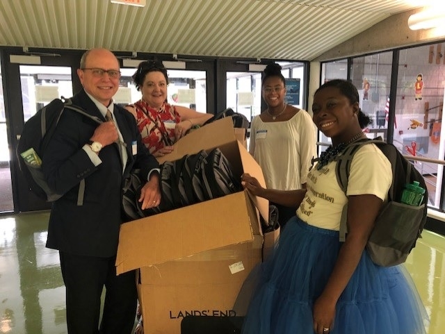 Firm President John J. Privitera handing out backpacks to 5th graders at Arbor Hill Elementary School through theREP's Community Outreach Program.
