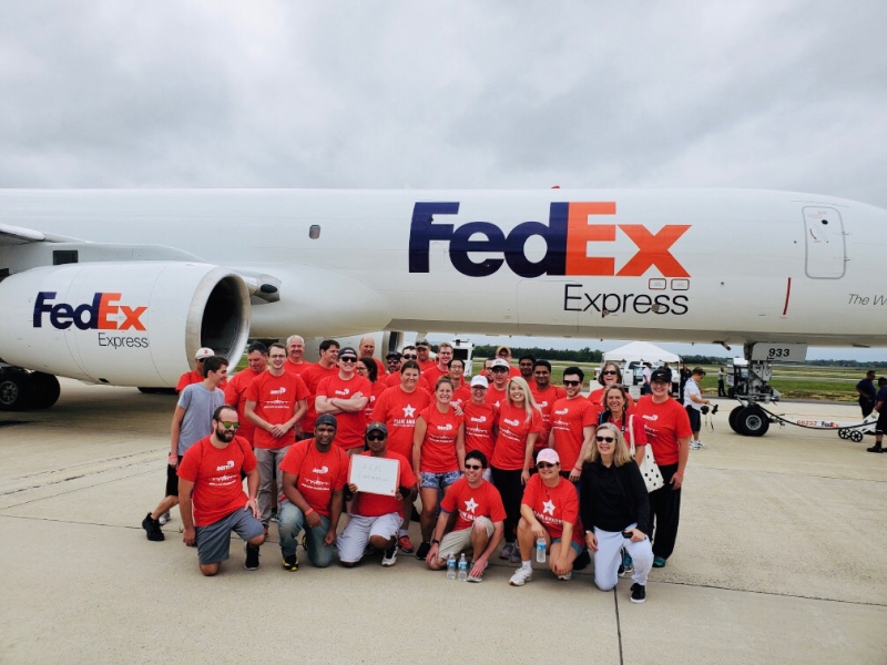 AEM employees pose at a plane-pulling event in support of the Special Olympics at Dulles Airport.