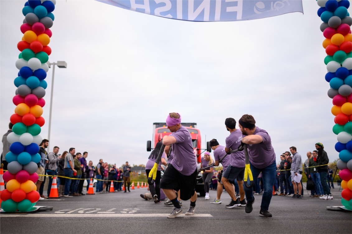 A team of TQL employees work together to pull a semi truck over the finishline during our Pull For A Cure Cancer Awareness Month event in October.