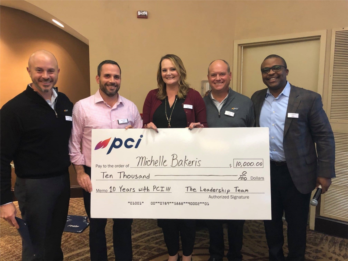 PCI's Leadership Team presents Michelle Bakeris with a $10,000 retention bonus for remaining with the company for 10 years.