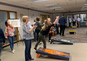 Colleagues participate in a little friendly competition during a division-wide cornhole tournament. 