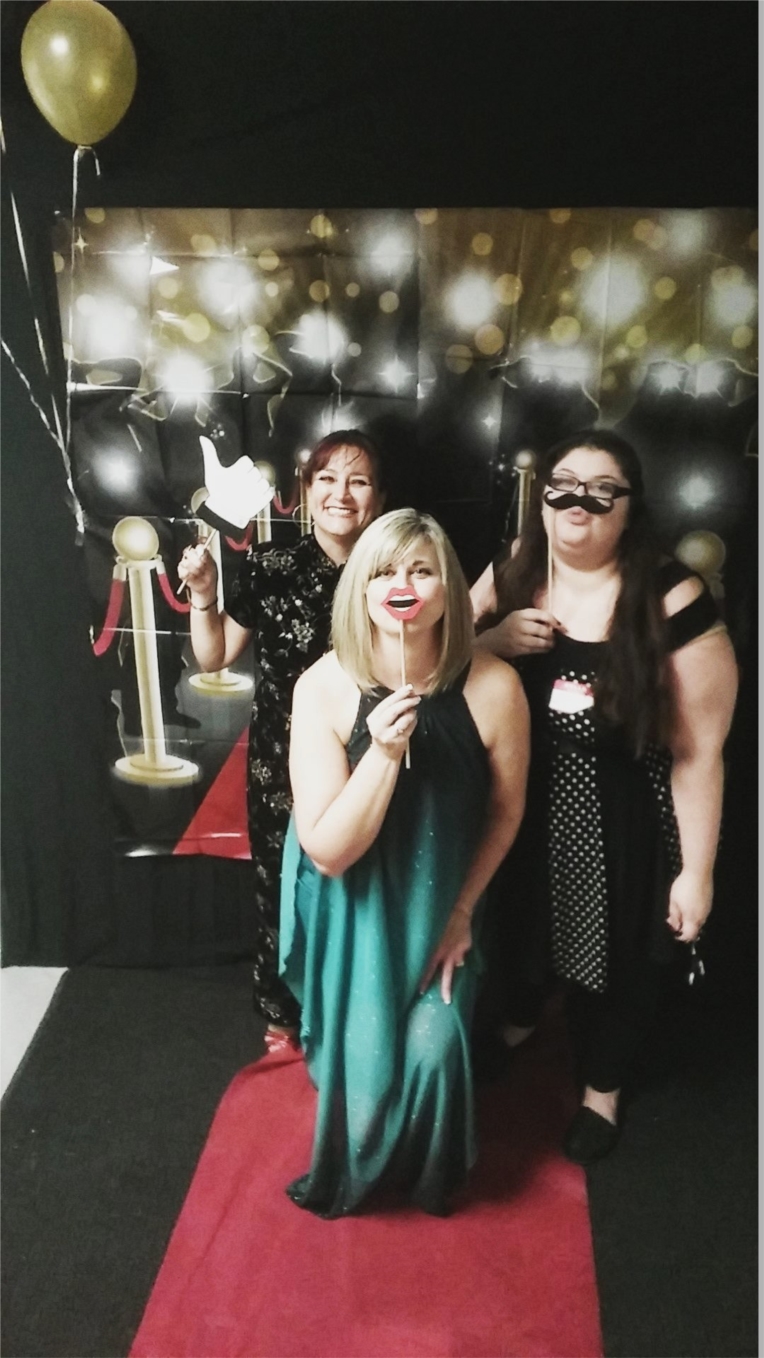 AnswerFirst Training Specialist Claudia Rosenfeld, left, Contact Center Manager, Barbie Rau, right, and HR Coordinator, center, Joan Stearns capturing their Red Carpet photo moment at the AnswerFirst end of the year holiday celebration.  