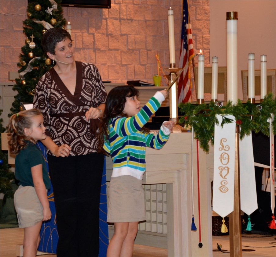 Kindergarten students lighting candles in chapel with Chaplain Leslie.  