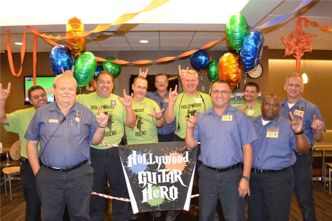Team Members from the Facilities department posing with the Guitar Hero ring that they constructed for our Hollywood Rocks week.